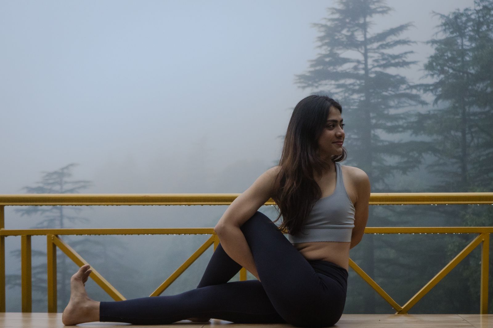 A woman practising yoga on a misty terrace in Dharamshala.