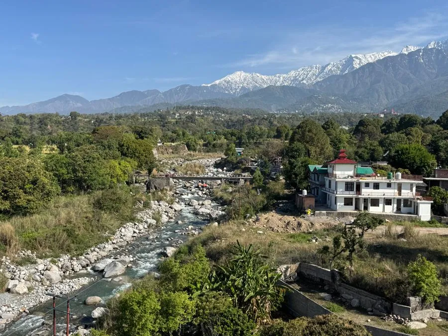 A river runs below the snow-capped Dhauladhar range near Dharamshala.