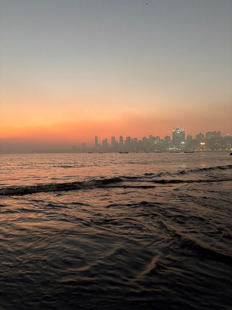 The Mumbai skyline across the sea at sunset.